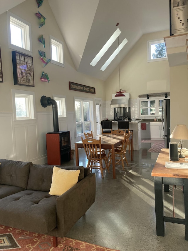 interior space featuring a wood stove, a wainscoted wall, and high vaulted ceiling