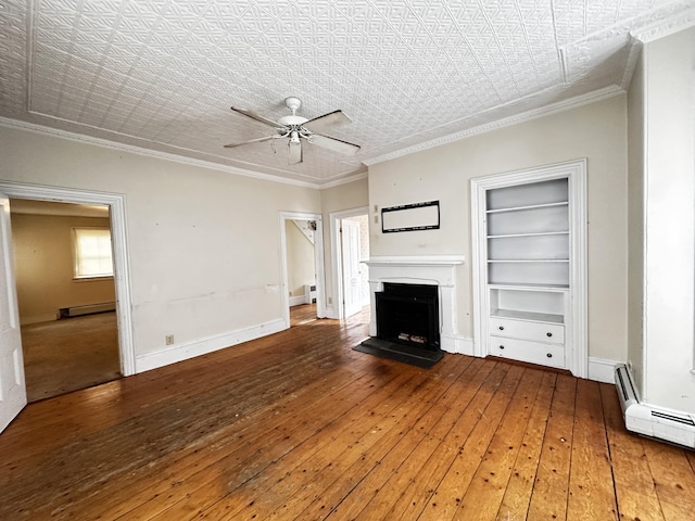 unfurnished living room featuring ceiling fan, a baseboard heating unit, built in shelves, hardwood / wood-style floors, and ornamental molding