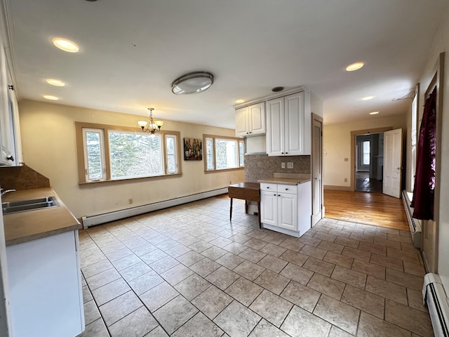 kitchen featuring sink, baseboard heating, white cabinets, and light tile floors