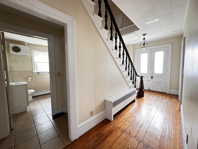 entrance foyer with wood-type flooring, radiator heating unit, and baseboard heating