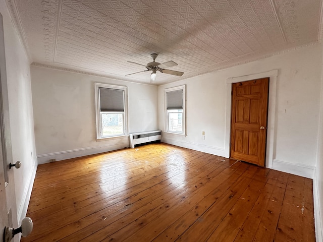 unfurnished room featuring ornamental molding, ceiling fan, hardwood / wood-style flooring, and radiator heating unit