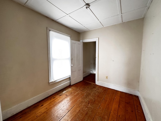 empty room featuring a drop ceiling and hardwood / wood-style floors