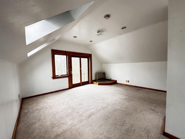 additional living space with lofted ceiling with skylight and carpet flooring