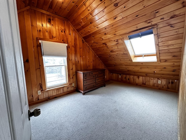 additional living space with wood walls, lofted ceiling with skylight, and wooden ceiling