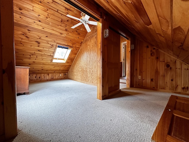 bonus room with wood walls, ceiling fan, lofted ceiling with skylight, light carpet, and wooden ceiling