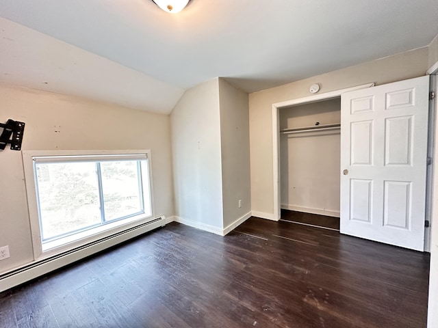 unfurnished bedroom featuring dark hardwood / wood-style flooring, a closet, vaulted ceiling, and a baseboard heating unit