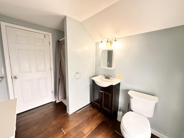 bathroom featuring toilet, vanity, hardwood / wood-style floors, and lofted ceiling