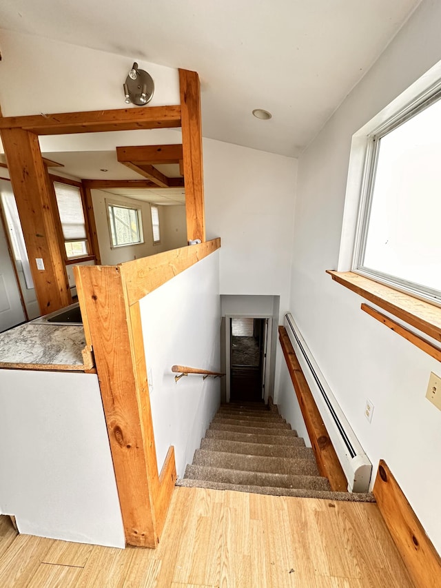 stairway featuring a baseboard radiator and light wood-type flooring