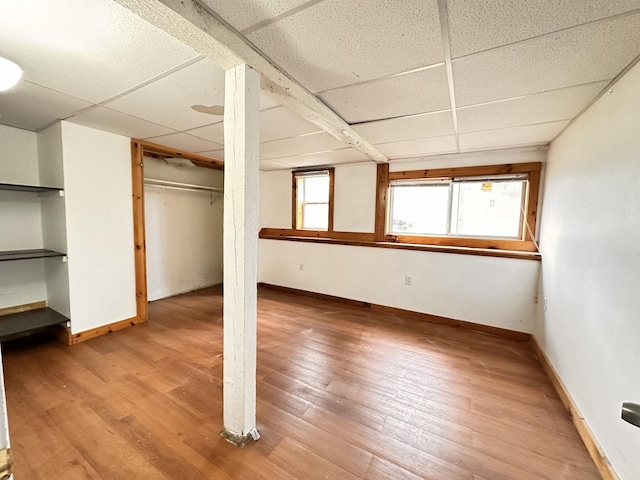 basement featuring a drop ceiling, plenty of natural light, and hardwood / wood-style floors