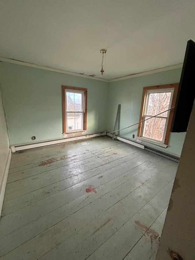 spare room featuring a healthy amount of sunlight, light wood-type flooring, and a baseboard radiator