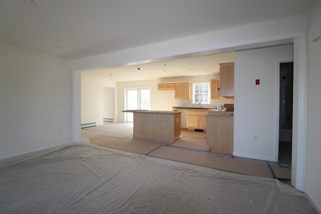 kitchen with light brown cabinets, a center island, a baseboard heating unit, and sink