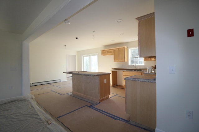 kitchen with a center island, sink, light brown cabinetry, and a baseboard radiator