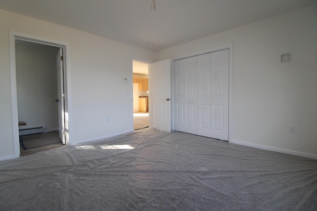 unfurnished bedroom with carpet flooring, a baseboard radiator, and a closet