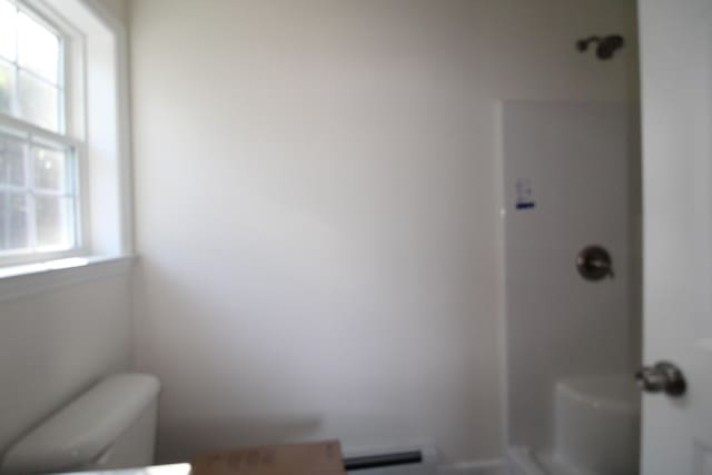 bathroom with a wealth of natural light, a baseboard radiator, and toilet