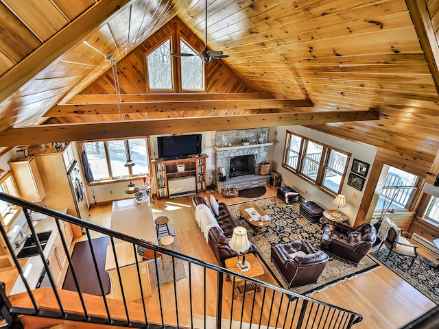 living room featuring high vaulted ceiling, hardwood / wood-style flooring, ceiling fan, a fireplace, and wood ceiling