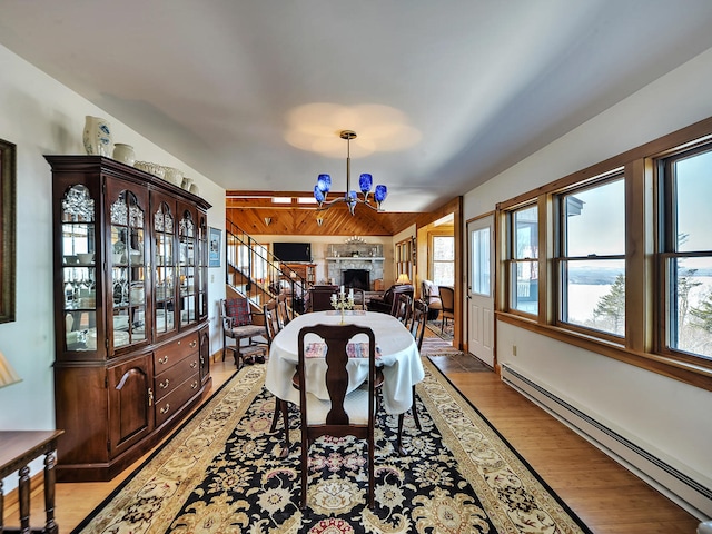 dining area with a chandelier, light wood-type flooring, and a baseboard radiator