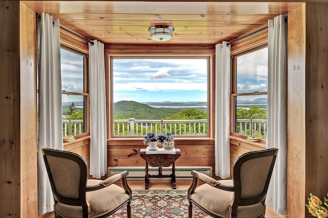 sunroom / solarium with baseboard heating, a mountain view, a healthy amount of sunlight, and wood ceiling