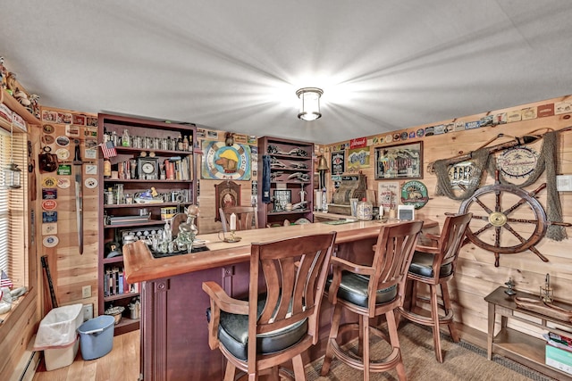 bar featuring butcher block counters, wooden walls, and a baseboard radiator