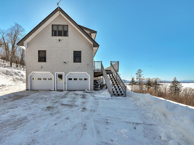 view of snow covered exterior featuring a garage and a deck