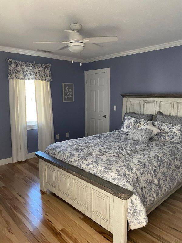 bedroom with ornamental molding, wood-type flooring, and ceiling fan