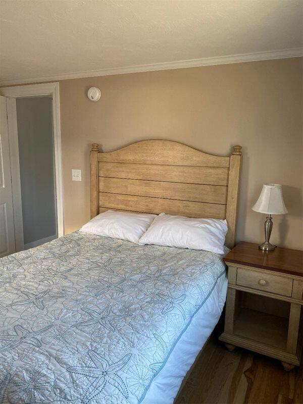 bedroom with crown molding and dark hardwood / wood-style floors