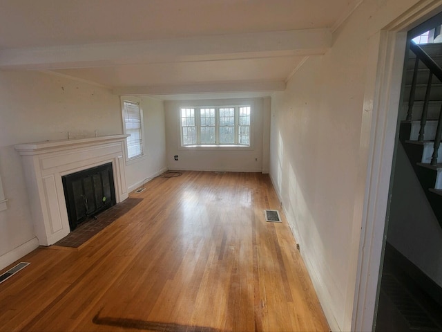 unfurnished living room with beamed ceiling and light hardwood / wood-style floors