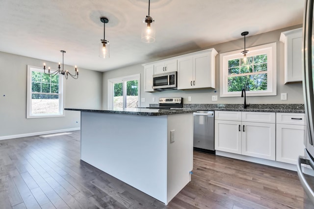 kitchen with decorative light fixtures, a kitchen island, stainless steel appliances, and dark wood-type flooring