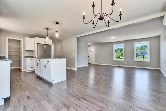 kitchen featuring a center island, pendant lighting, wood-type flooring, white cabinets, and stainless steel fridge