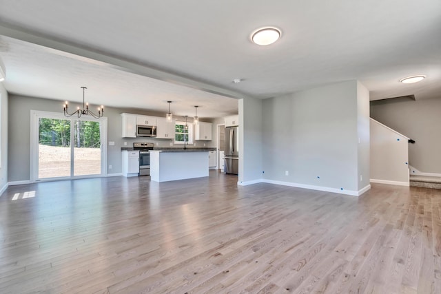 unfurnished living room with a notable chandelier and hardwood / wood-style floors