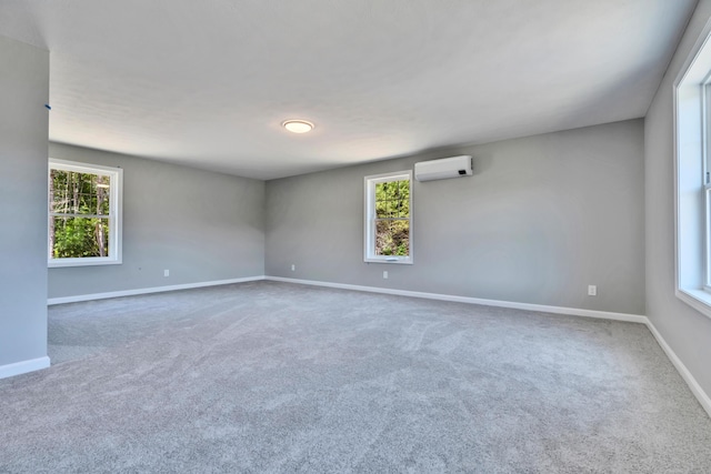 empty room featuring a healthy amount of sunlight, a wall mounted AC, and carpet floors