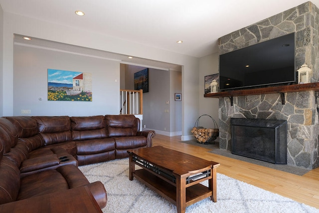 living room featuring a fireplace, baseboards, wood finished floors, and recessed lighting