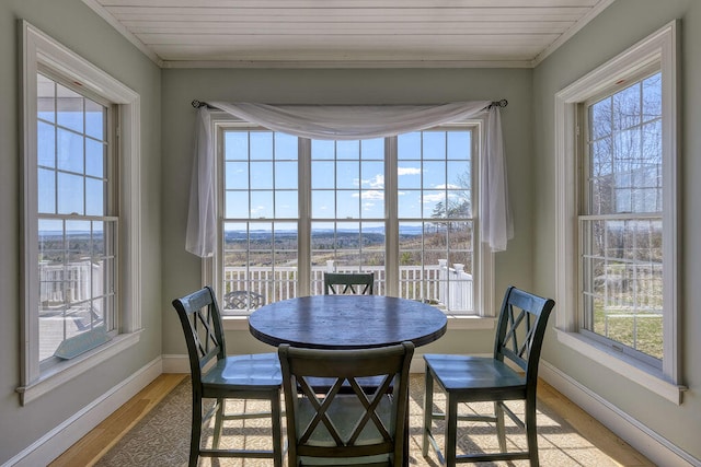 dining room featuring light wood-style floors, wood ceiling, and baseboards