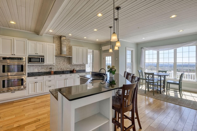 kitchen featuring wall chimney exhaust hood, stainless steel appliances, dark countertops, and white cabinets