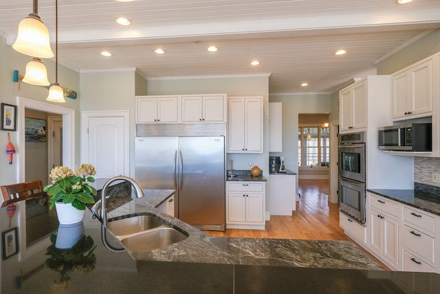 kitchen with stainless steel appliances, a sink, decorative light fixtures, and white cabinets