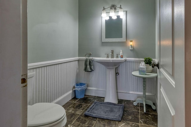 bathroom featuring marble finish floor, a wainscoted wall, and toilet