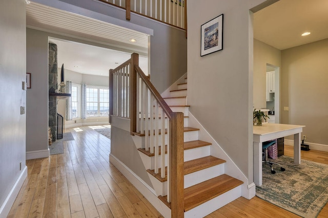 staircase with hardwood / wood-style flooring, recessed lighting, baseboards, and a tile fireplace