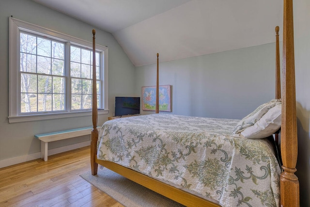 bedroom with lofted ceiling, light wood finished floors, and baseboards