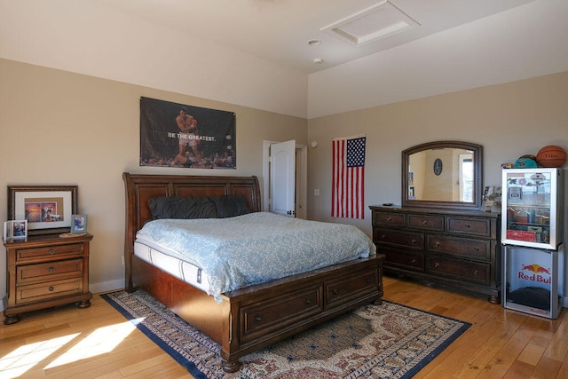 bedroom featuring vaulted ceiling, light wood-type flooring, attic access, and baseboards