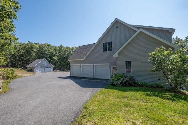 view of side of home featuring a yard, driveway, and an outdoor structure