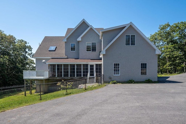 back of house with a sunroom, fence, and roof with shingles