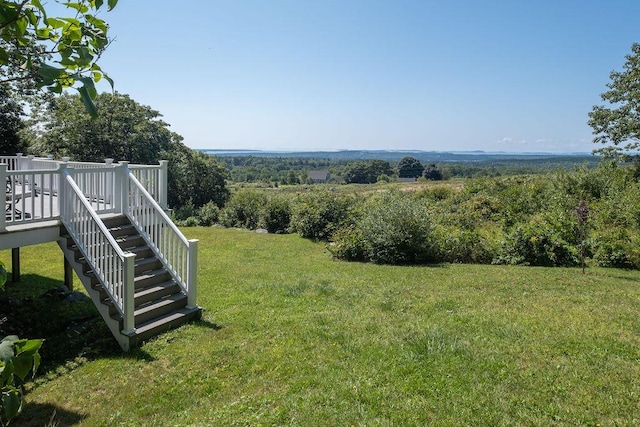 view of yard with a rural view, a wooden deck, and stairs