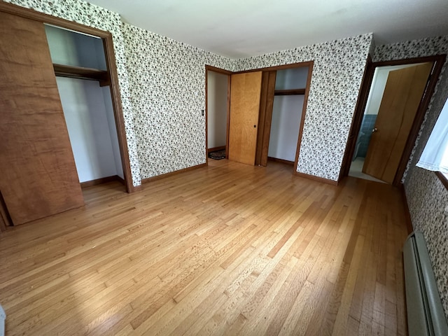 unfurnished bedroom featuring light wood-type flooring and a baseboard radiator