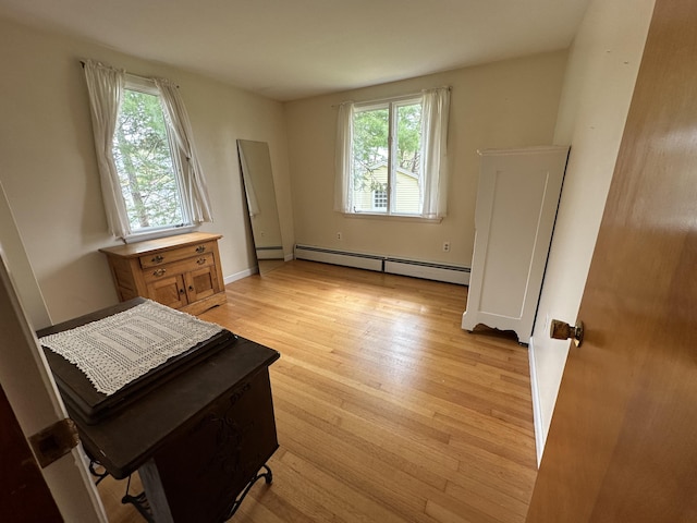 bedroom with light wood-type flooring, multiple windows, and a baseboard radiator