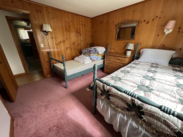 carpeted bedroom featuring wood walls