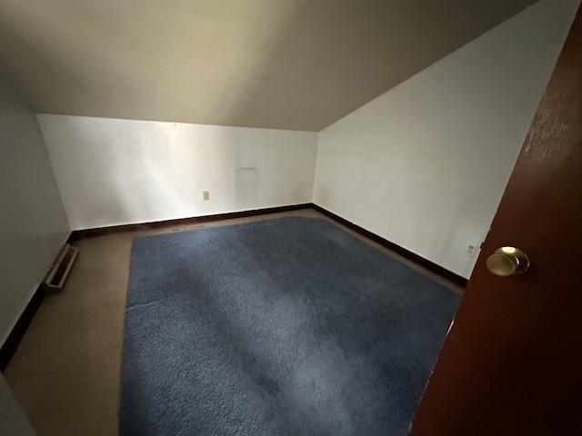 bonus room featuring a baseboard heating unit, dark colored carpet, and lofted ceiling