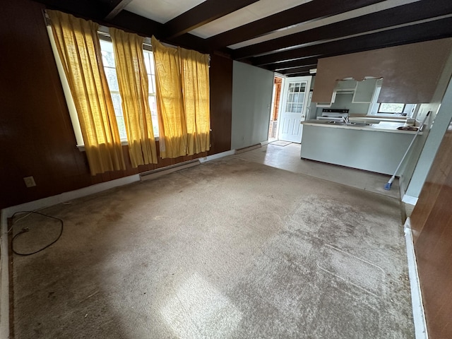 unfurnished living room with sink, baseboard heating, and beamed ceiling