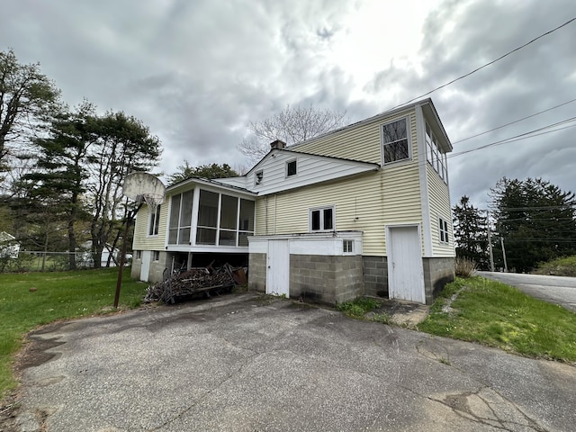 view of property exterior featuring a sunroom and a lawn