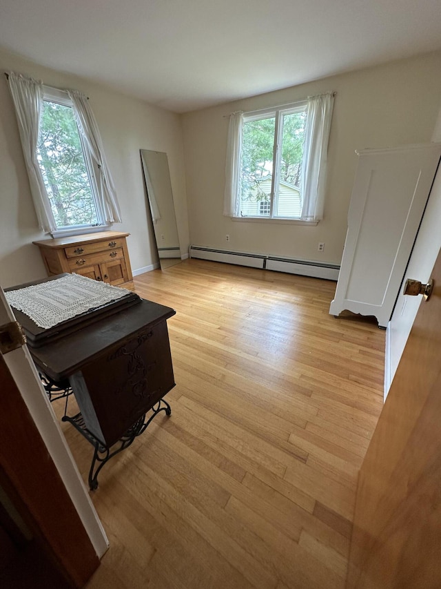 interior space featuring a wealth of natural light, light hardwood / wood-style floors, and a baseboard radiator