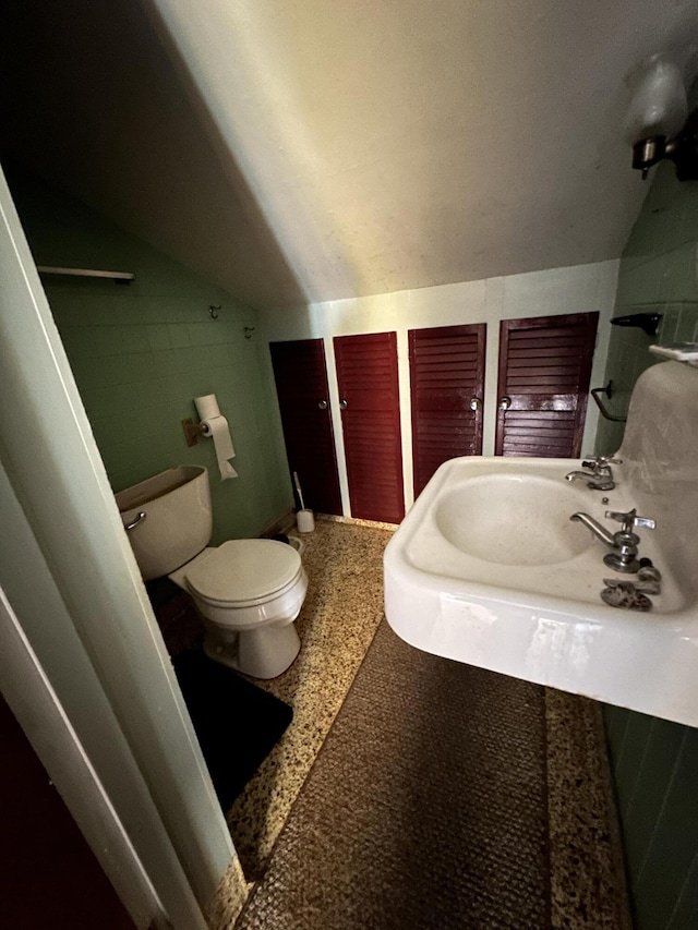 bathroom featuring sink, toilet, and lofted ceiling