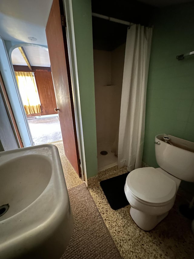 bathroom featuring toilet, sink, and curtained shower